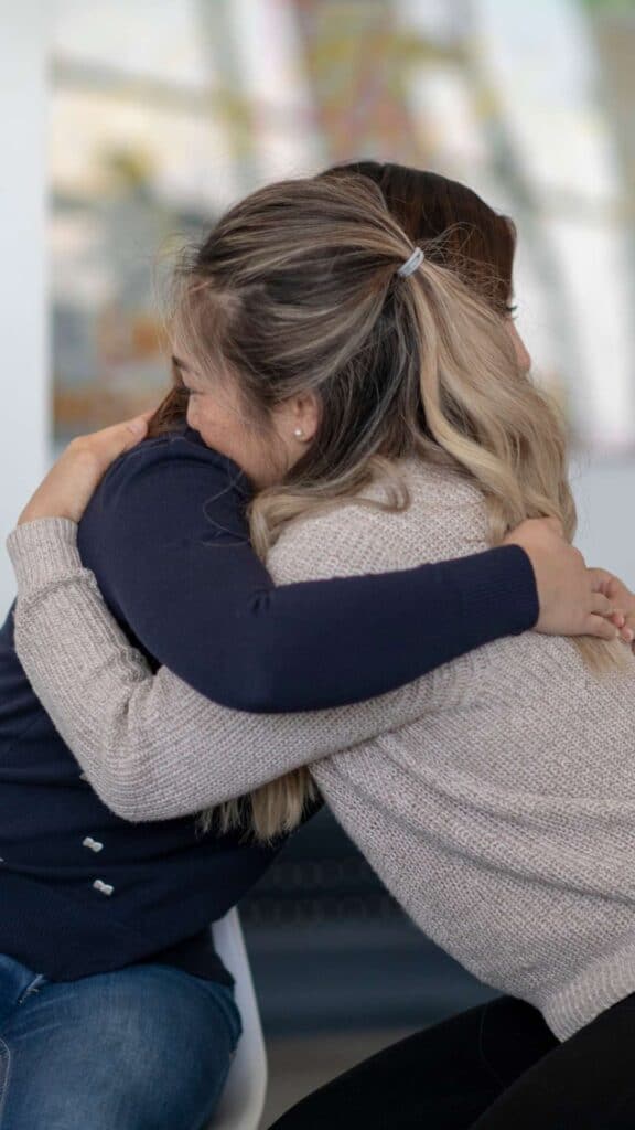 Two Women Hugging During Group Therapy While They're in Residential Inpatient Addiction Treatment